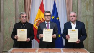 Tres personas sosteniendo documentos en un acuerdo sobre reparaci&oacute;n de v&iacute;ctimas de abusos.