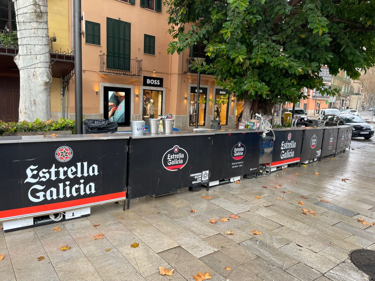 Barra de Estrella Galicia en una calle con &aacute;rboles y tiendas