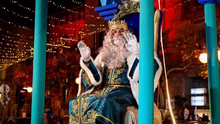 Melchor en la Cabalgata de Reyes Magos en Palma, rodeado de luces festivas.