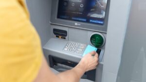 Persona usando un cajero autom&aacute;tico para realizar una transacci&oacute;n bancaria