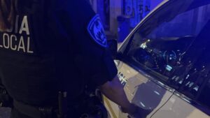Agente de polic&iacute;a local deteniendo un veh&iacute;culo en la noche