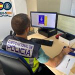 Agente de polic&iacute;a trabajando en un escritorio con computadoras