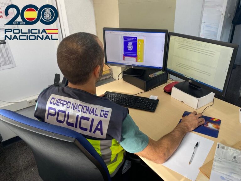 Agente de polic&iacute;a trabajando en un escritorio con computadoras