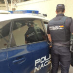 Agente de la Policía Nacional junto a un coche patrulla en Palma.
