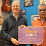 Dos hombres sosteniendo un cheque de donación de 3284 euros