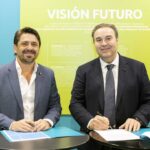 Dos hombres firmando un convenio en un evento de turismo