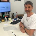 M&eacute;dico sentado en su escritorio con computadora y documentos