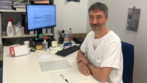 M&eacute;dico sentado en su escritorio con computadora y documentos