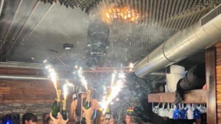 Celebraci&oacute;n en un local nocturno con fuegos artificiales y humo en el aire