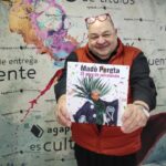 Hombre sosteniendo un libro titulado Mad&ograve; Pereta en un fondo colorido