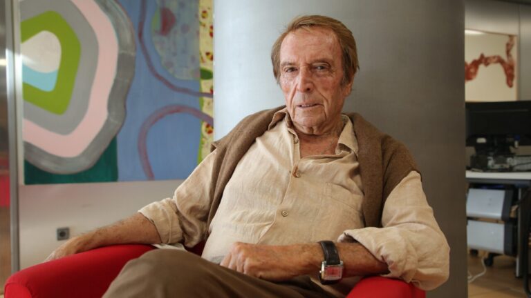 Miguel Soler sentado en un sillón rojo, rodeado de arte moderno.