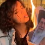 Mujer quemando una imagen del líder supremo de Irán durante una protesta