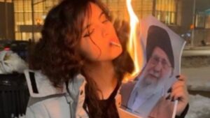 Mujer quemando una imagen del líder supremo de Irán durante una protesta