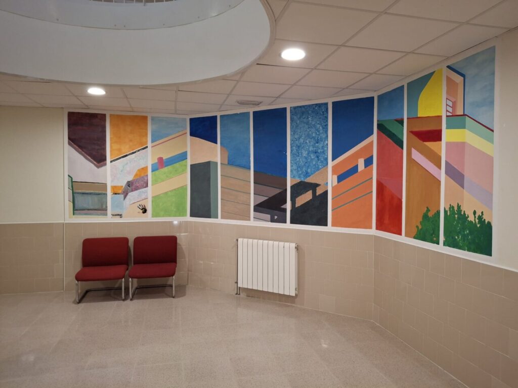 Mural colorido en la pared de un local con asientos rojos