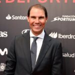 Rafa Nadal sonriendo en un evento deportivo con fondo oscuro