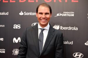 Rafa Nadal sonriendo en un evento deportivo con fondo oscuro