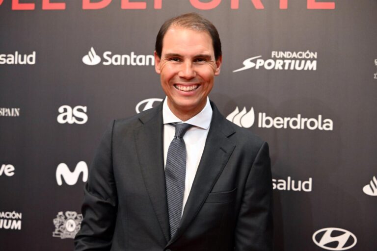 Rafa Nadal sonriendo en un evento deportivo con fondo oscuro