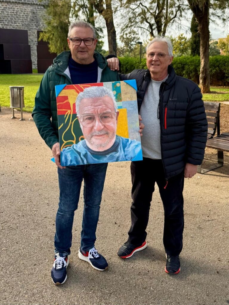 Rafael Palma sosteniendo un retrato en un parque con un amigo.