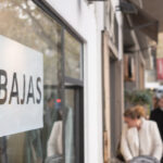 Cartel de rebajas en una tienda en Baleares con gente de fondo