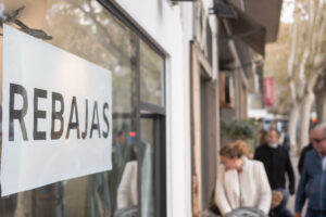 Cartel de rebajas en una tienda en Baleares con gente de fondo