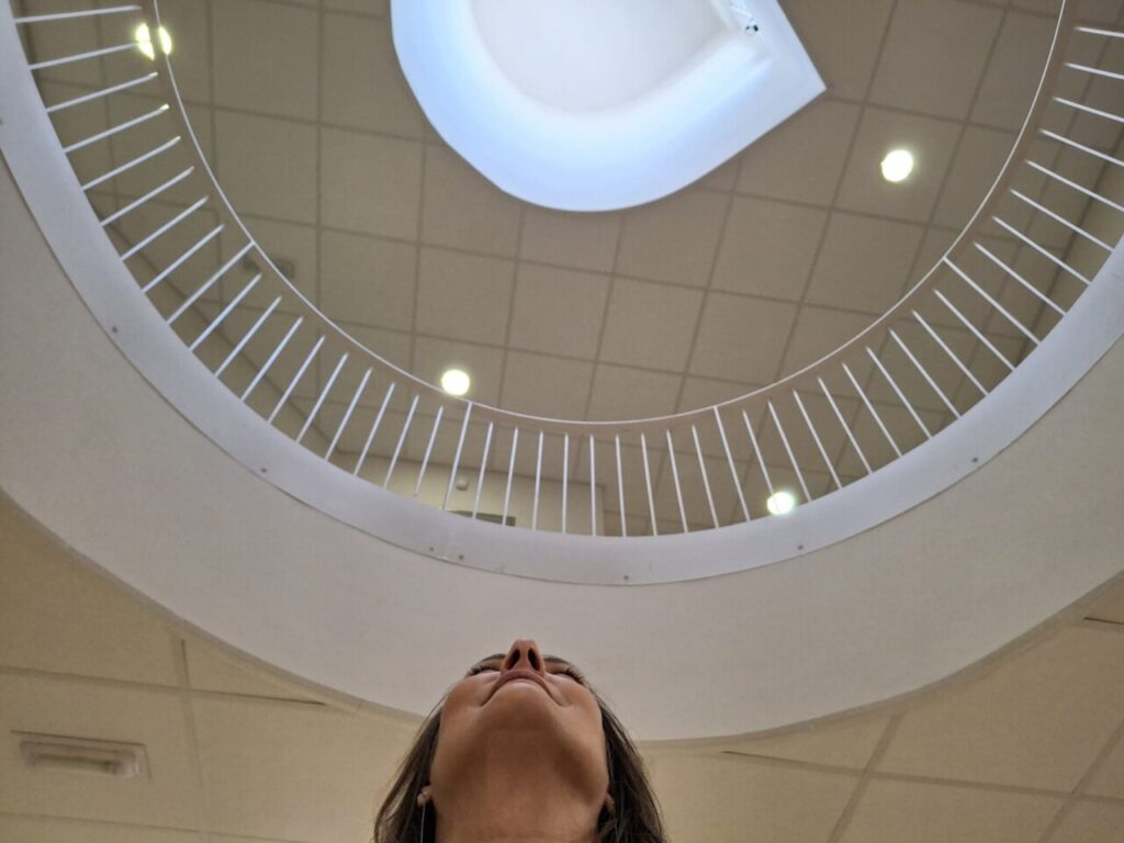 Mujer mirando hacia arriba en una escalera circular con barandilla blanca