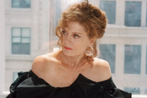 Susan Sarandon posando con un vestido negro en un entorno luminoso.