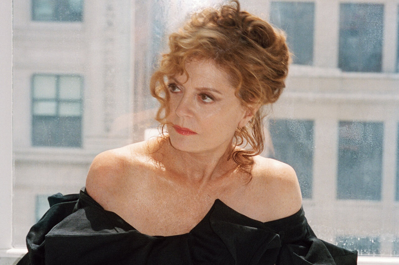 Susan Sarandon posando con un vestido negro en un entorno luminoso.