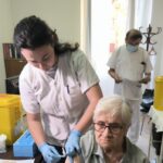 Una mujer mayor recibiendo la vacuna contra la gripe en un centro sanitario.