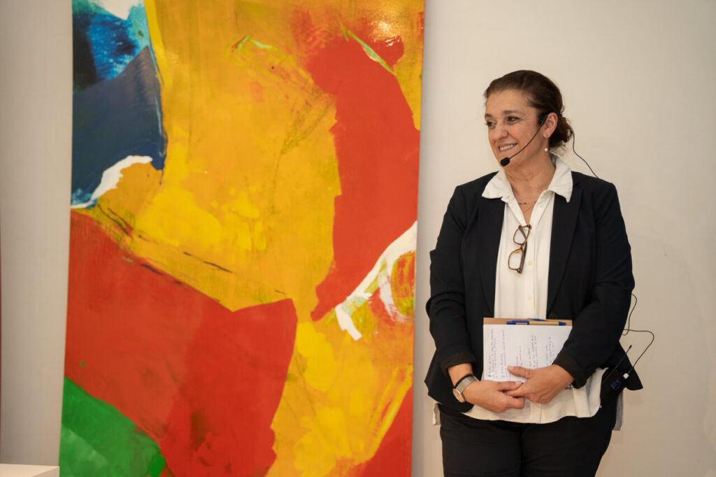 Mujer de pie junto a una pintura colorida en un evento