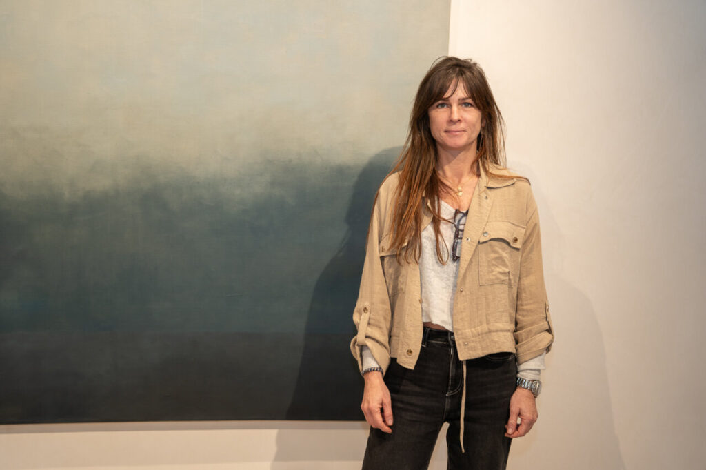 Mujer de pie frente a una pintura abstracta en una galer&iacute;a