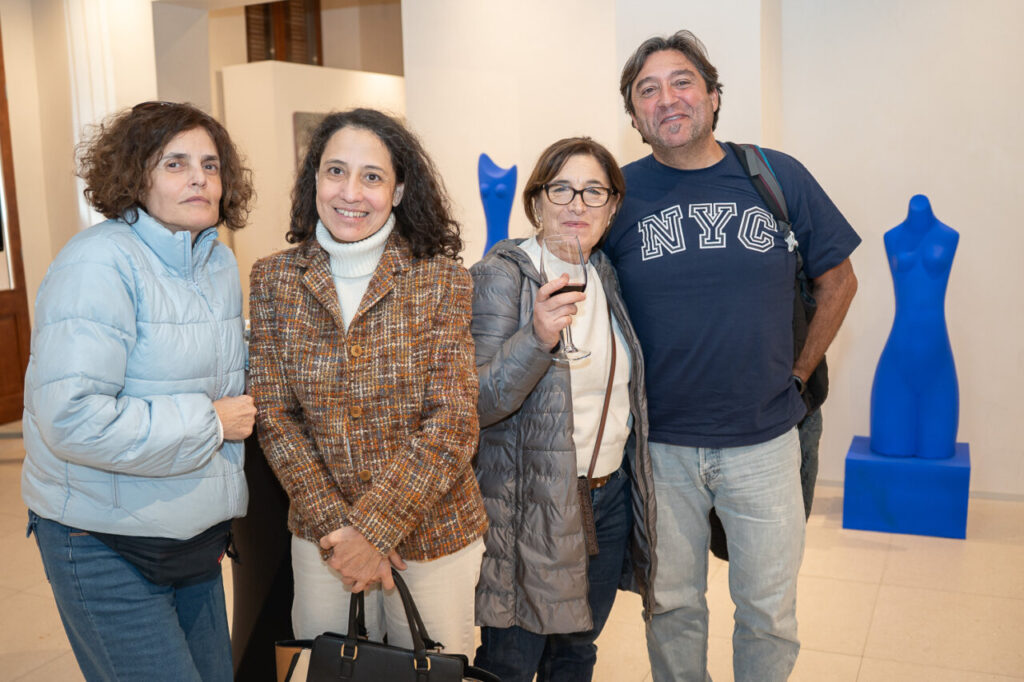 Cuatro personas posando en un evento con esculturas azules de fondo