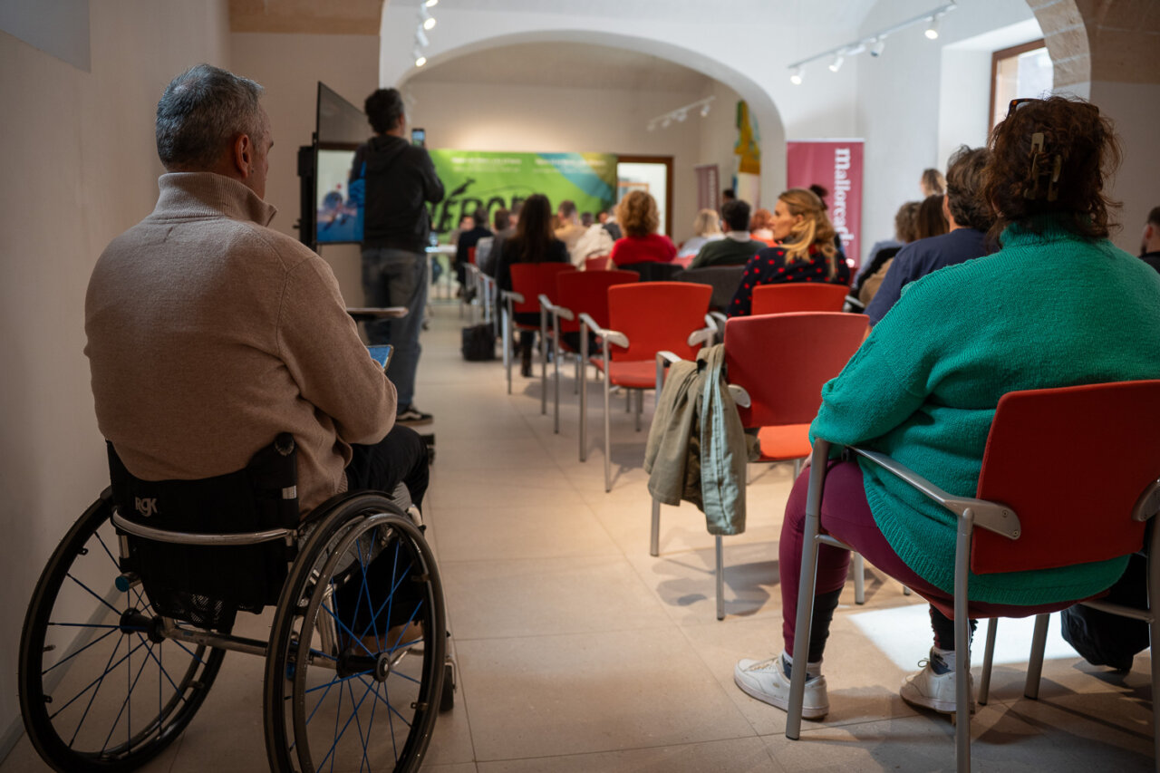 Asistentes a un evento en un espacio interior con sillas rojas