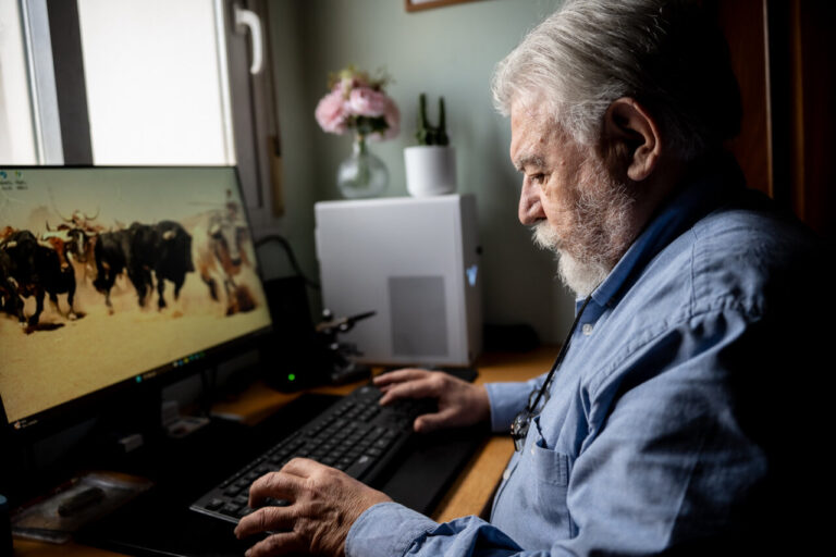Hombre mayor trabajando en computadora con fondo de ganado