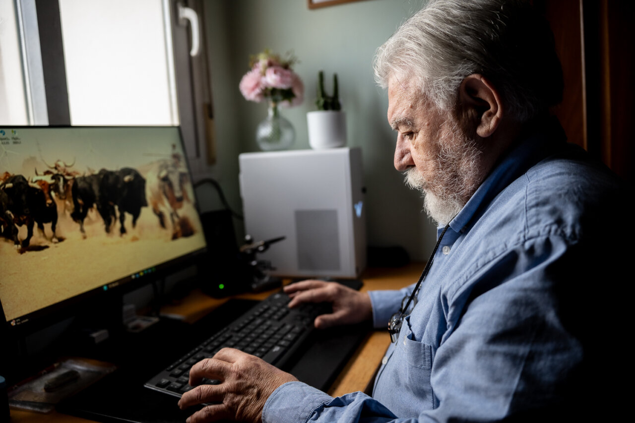 Hombre mayor trabajando en computadora con fondo de ganado