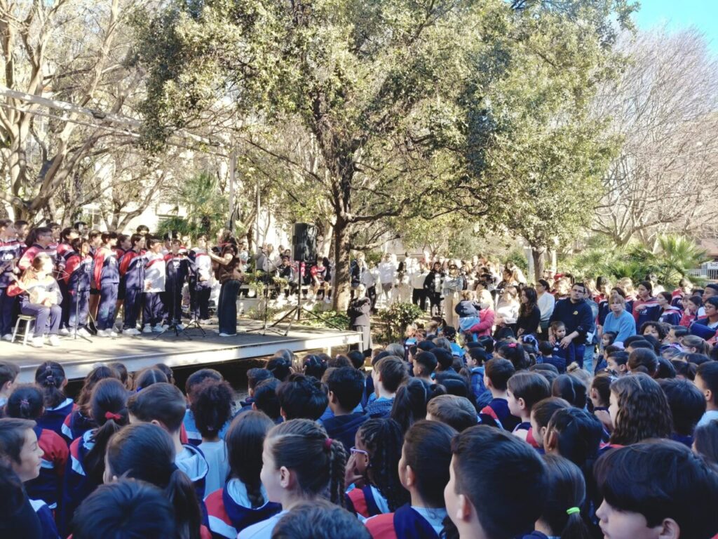 Evento escolar con ni&ntilde;os y adultos en un escenario al aire libre