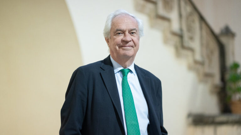 Hombre de pie en un evento de presentaci&oacute;n de libro con fondo decorativo