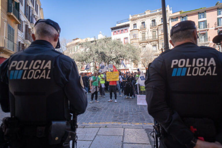 Policías locales observan una protesta en Palma con pancartas.