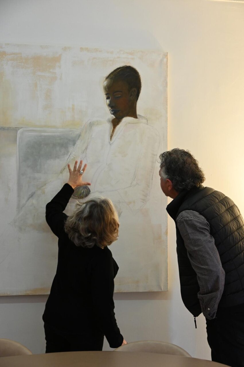 Marta Muniesa y un hombre observando una pintura en una galer&iacute;a.