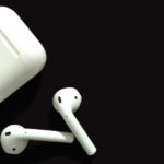 Auriculares Bluetooth y su estuche sobre fondo oscuro