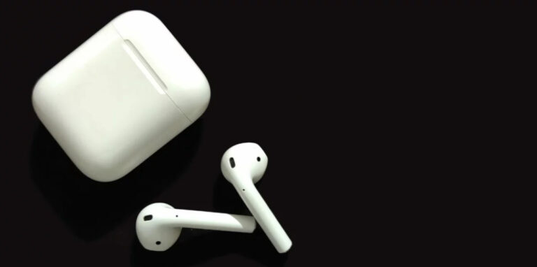 Auriculares Bluetooth y su estuche sobre fondo oscuro