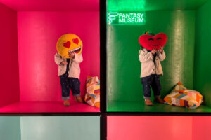 Ni&ntilde;os en un museo interactivo sosteniendo cojines con emoticonos