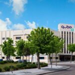 Edificio del Qube Technology Park rodeado de árboles y cielo azul