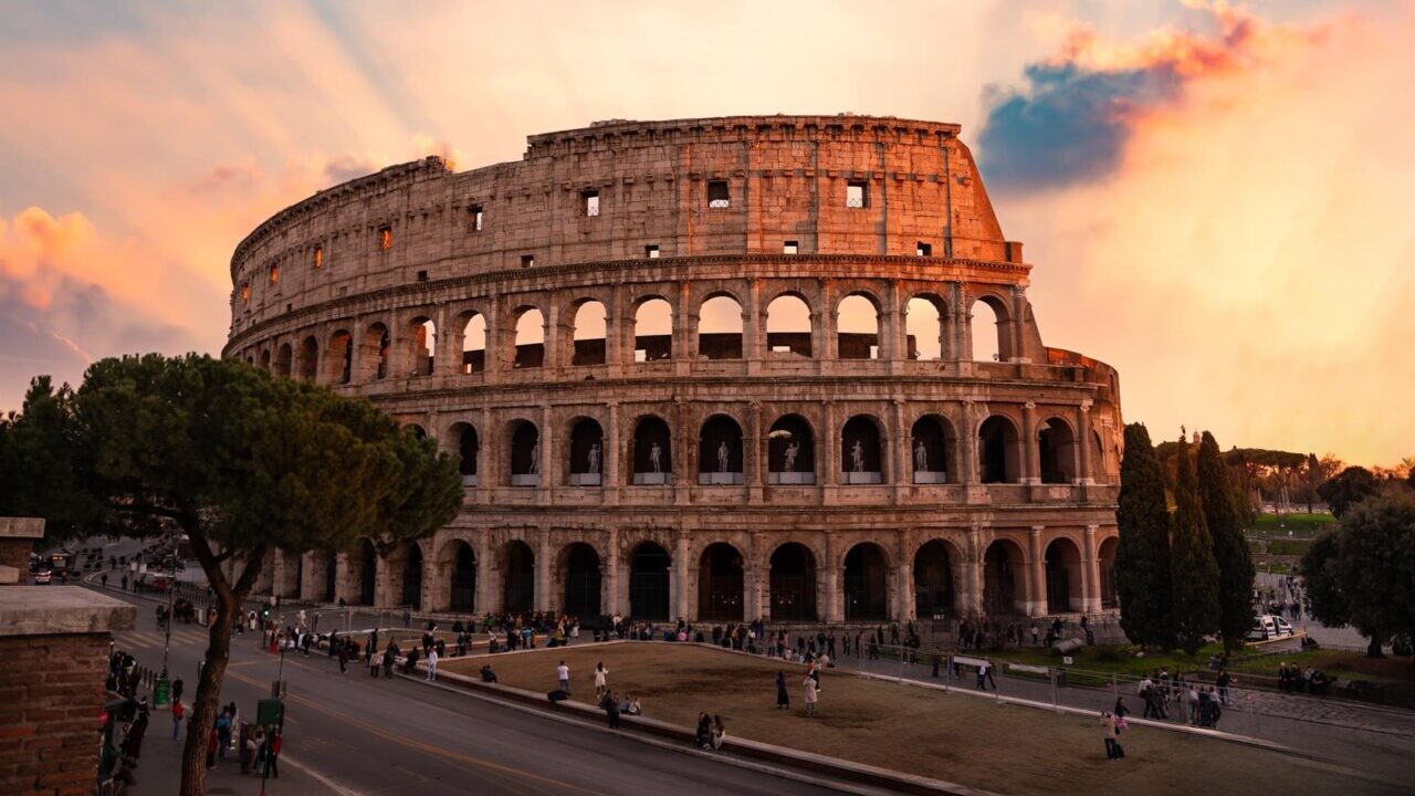 Vista del Coliseo en Roma durante el atardecer con cielo colorido