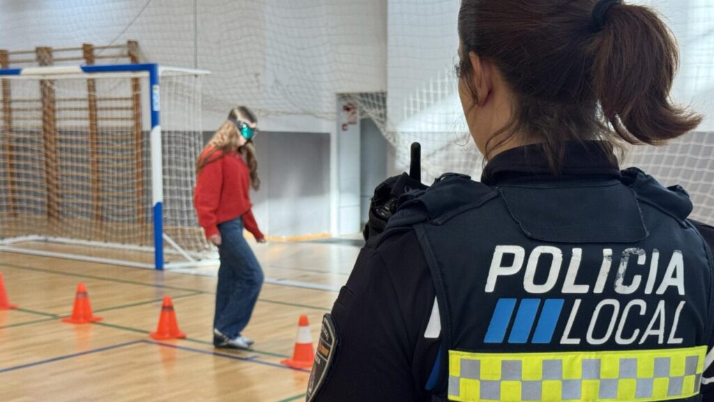 Agente observando a estudiante usando gafas simuladoras de efectos de drogas