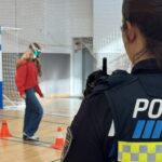 Agente observando a estudiante usando gafas simuladoras de efectos de drogas