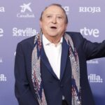 Fernando Esteso en un evento, saludando con una mano levantada.