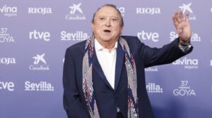 Fernando Esteso en un evento, saludando con una mano levantada.