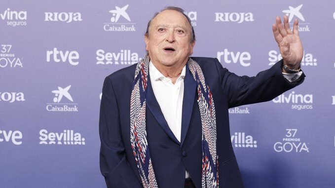 Fernando Esteso en un evento, saludando con una mano levantada.