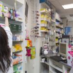 Interior de una farmacia con productos y un farmac&eacute;utico atendiendo