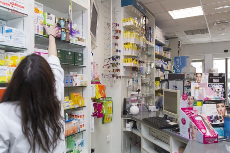 Interior de una farmacia con productos y un farmac&eacute;utico atendiendo
